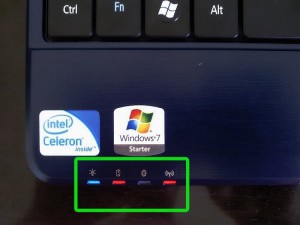 Fotografia do canto inferior esquerdo de um notebook com adesivo Windows 7 e Intel Celeron e painel de luzes indicadoras de bateria