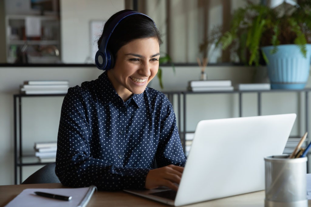 mulher jovem utilizando um notebook e sorrindo