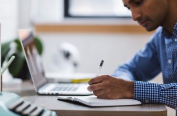 Homem fazendo anotações sobre memória ram 16gb com o notebook ao lado