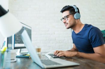 Homem jovem utilizando um notebook e headphone sem fio