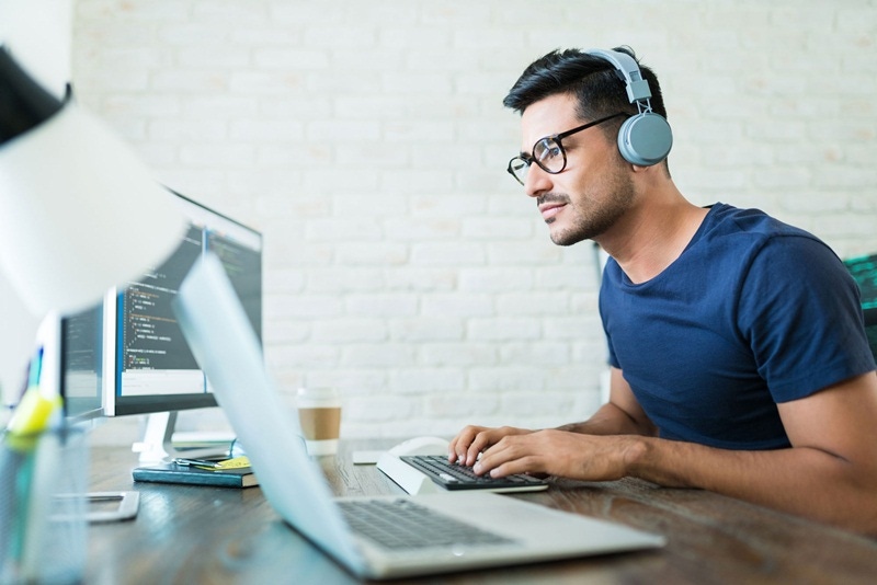 Homem jovem utilizando um notebook e headphone sem fio