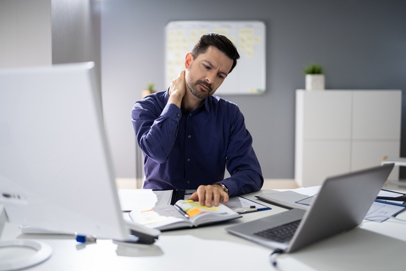 homem sem ergonomia no home office e com dores no pescoço