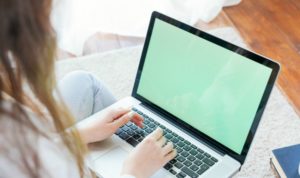 mulher mexendo em um notebook no colo