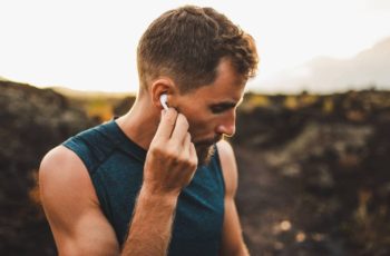 homem jovem e loiro utilizando fone de ouvido para celular