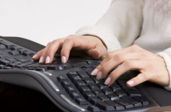 mão masculina em um teclado ergonômico preto