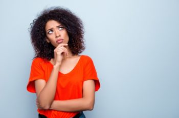 Mulher jovem, com cabelo cacheado, com expressão de dúvida