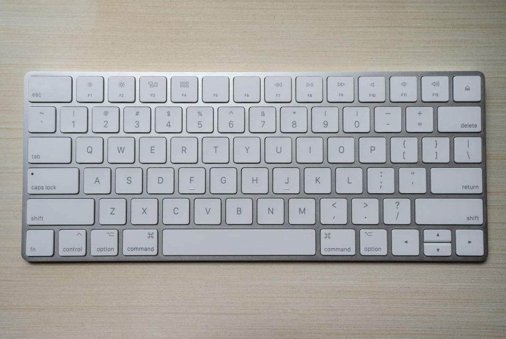 teclado apple branco sobre fundo de madeira