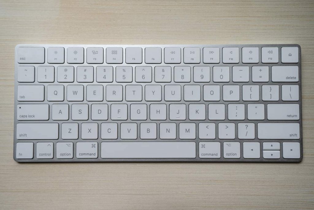 teclado apple branco sobre fundo de madeira