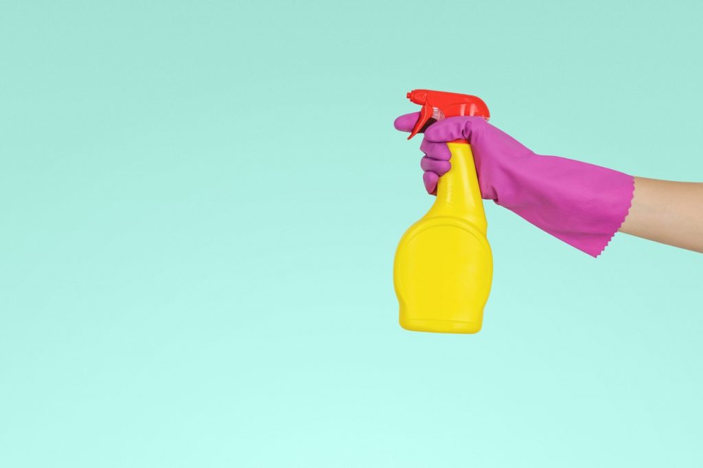 Pessoa segurando com uma luva um spray de limpeza