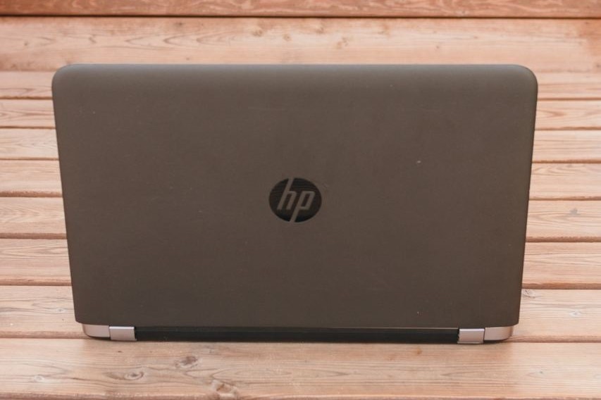 Notebook HP com a tela aberta sobre piso de madeira