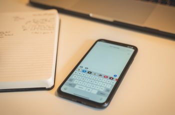 Iphone com teclado iphone em sua tela ao lado de um caderno em uma mesa