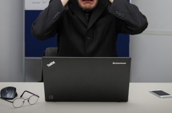 Homem desesperado com a mão na cabeça porque tela notebook fica piscando