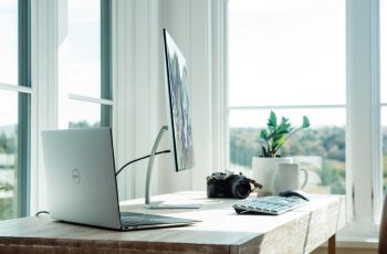 Notebook, teclado e mouse dell sobre mesa ao lado de uma janela
