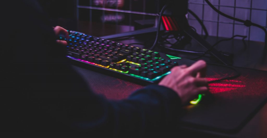 Teclado com LED RGB com gamer jogando nele