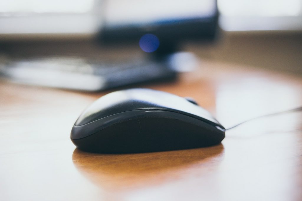 Mouse dell com teclado no fundo desfocado sobre mesa de madeira
