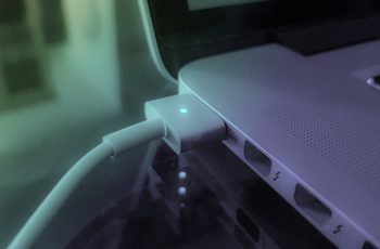 carregador de bateria de notebook conectado em um macbook com a luz verde acesa