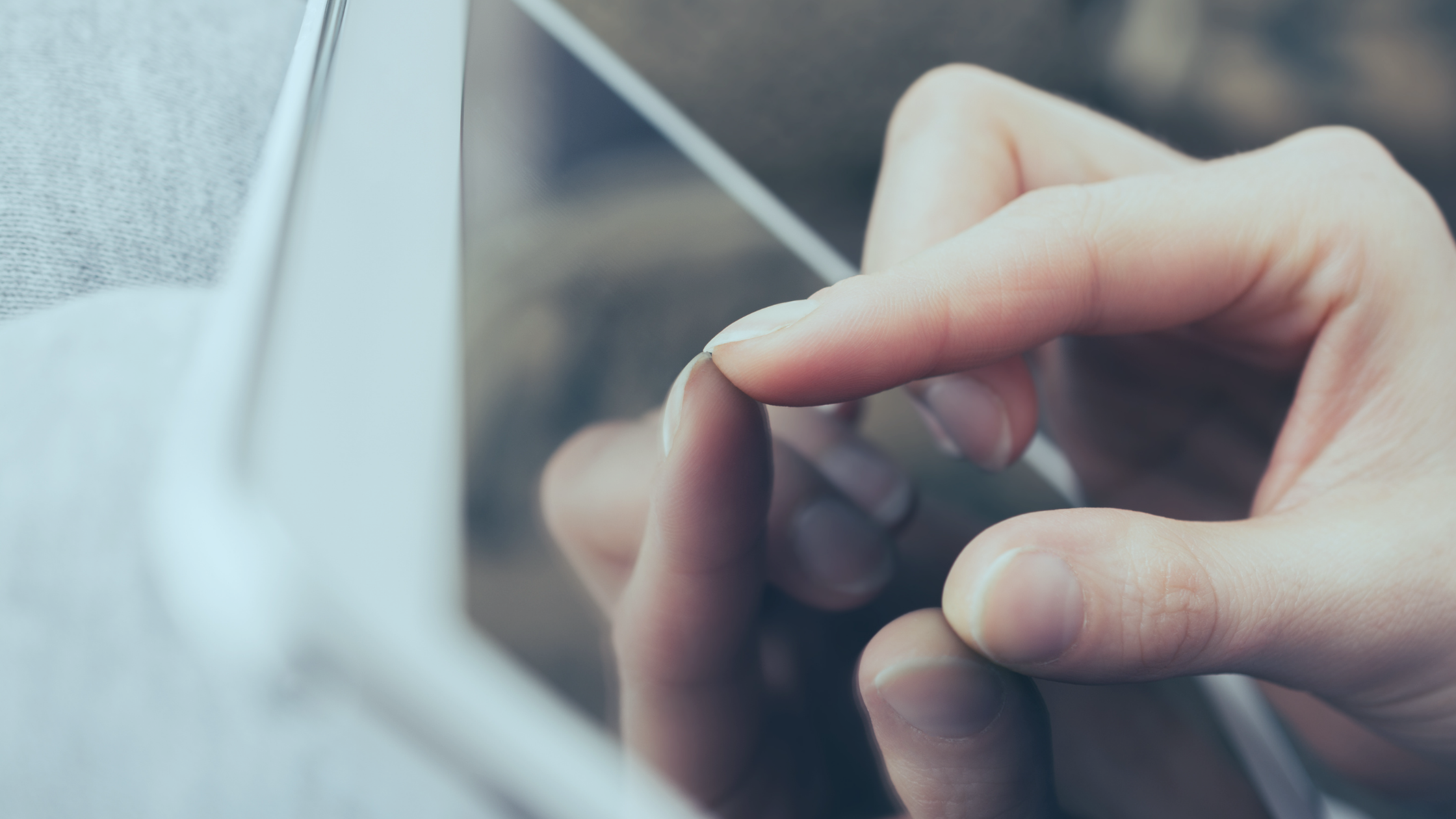 Dedos fazendo o movimento de zoom em uma tela de pc