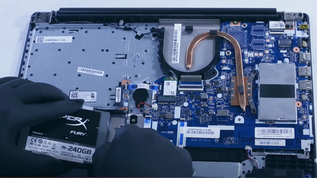 Homem com luvas instalando SSD em notebook Lenovo