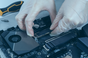 Homem instalando um SSD no interior de um notebook com luvas