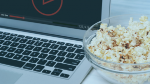 Notebook passando uma série na tela com um pote de pipoca ao lado