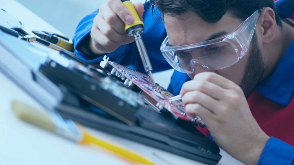 Técnico de informática apoiado sobre uma placa enquanto realiza uma manutenção.