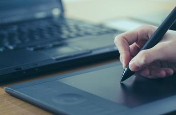 Mão desenhando em uma mesa digitalizadora com caneta