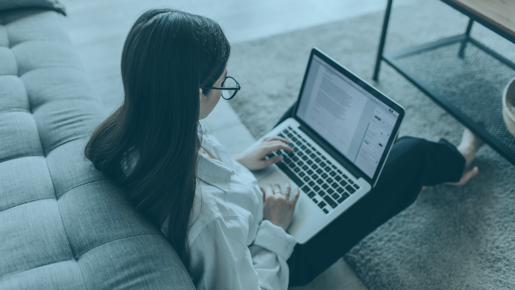 Imagem de uma mulher sentada no chão com um notebook no colo.