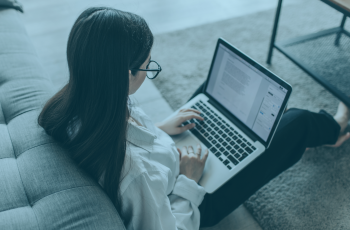 Imagem de uma mulher sentada no chão com um notebook no colo.