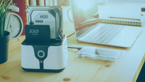 Porta objetos com um SSD e HD, ao fundo, um notebook.